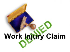 Top view of a rubber stamp with a giant word "Work injury claim - denied " isolated on white background