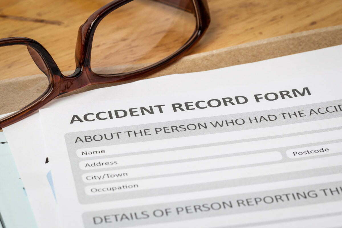 18441500 accident report application form on brown envelope and eyeglass