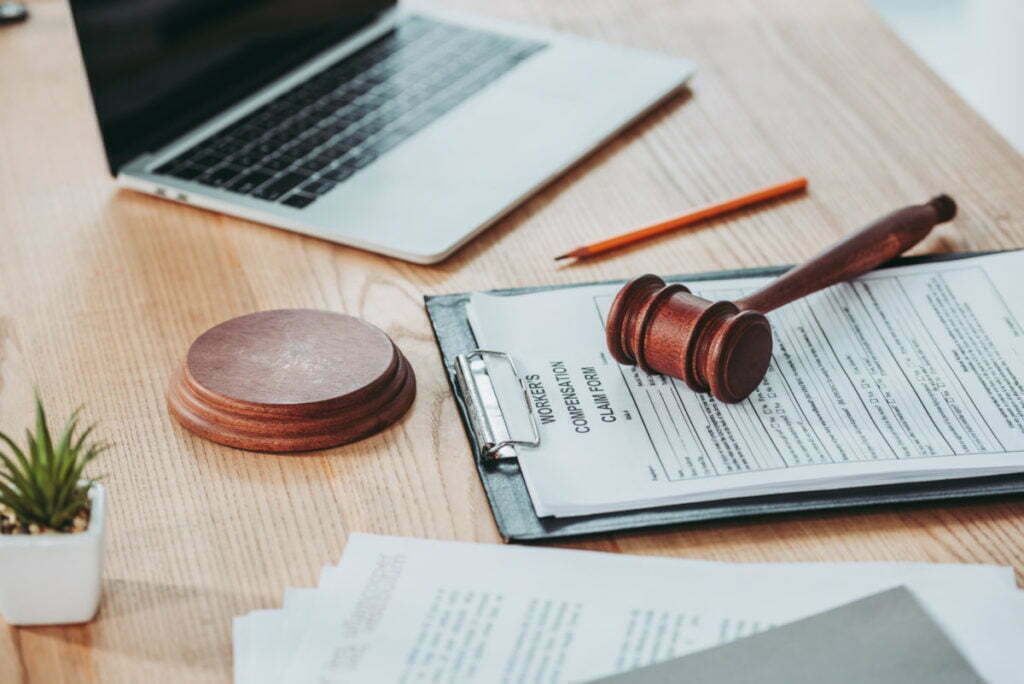 Clipboard with a workers compensation claim form and a gavel on a desk